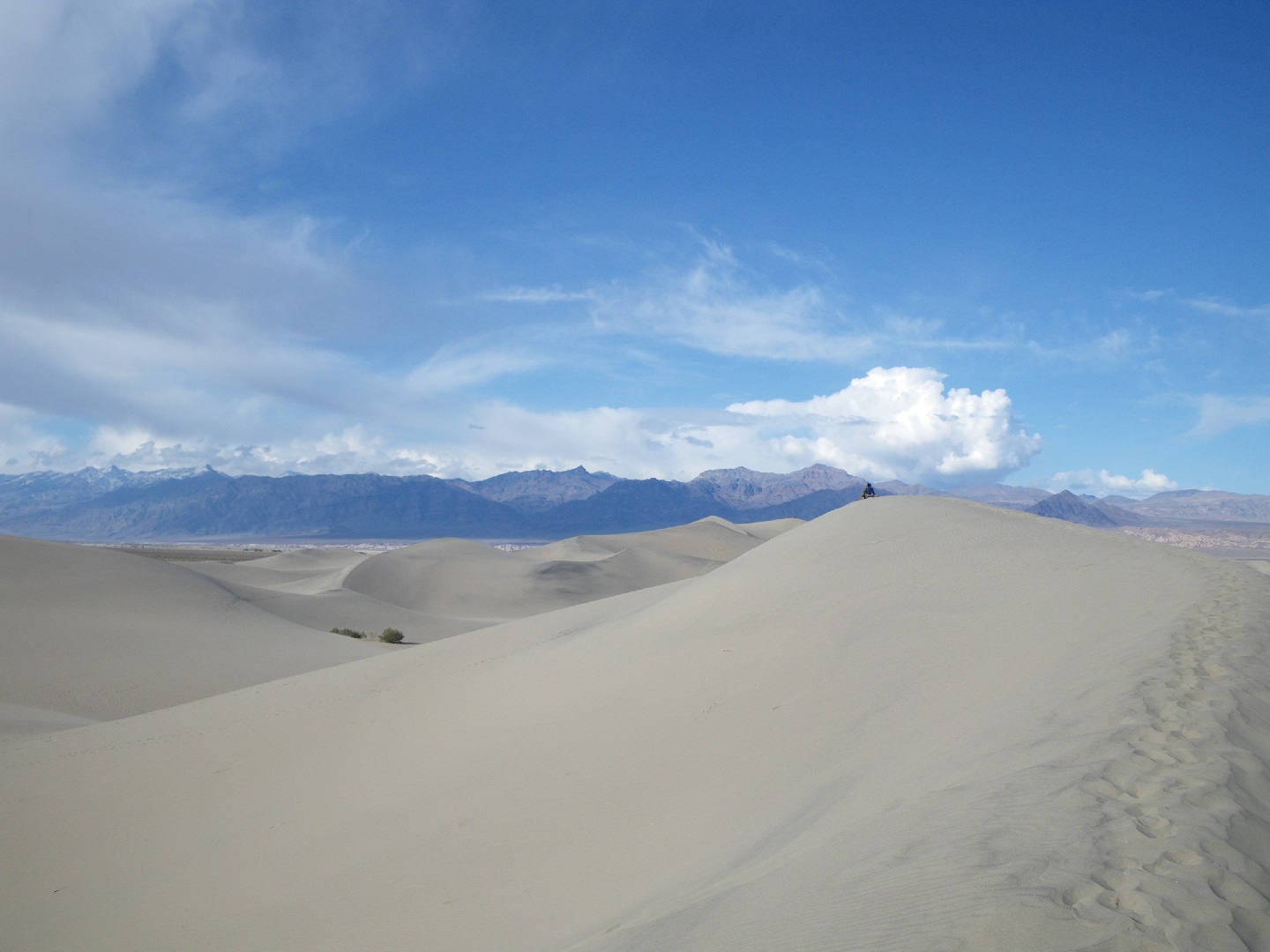 Skysand (photo of a person sitting on a sand dune, dwarfed by the sky)